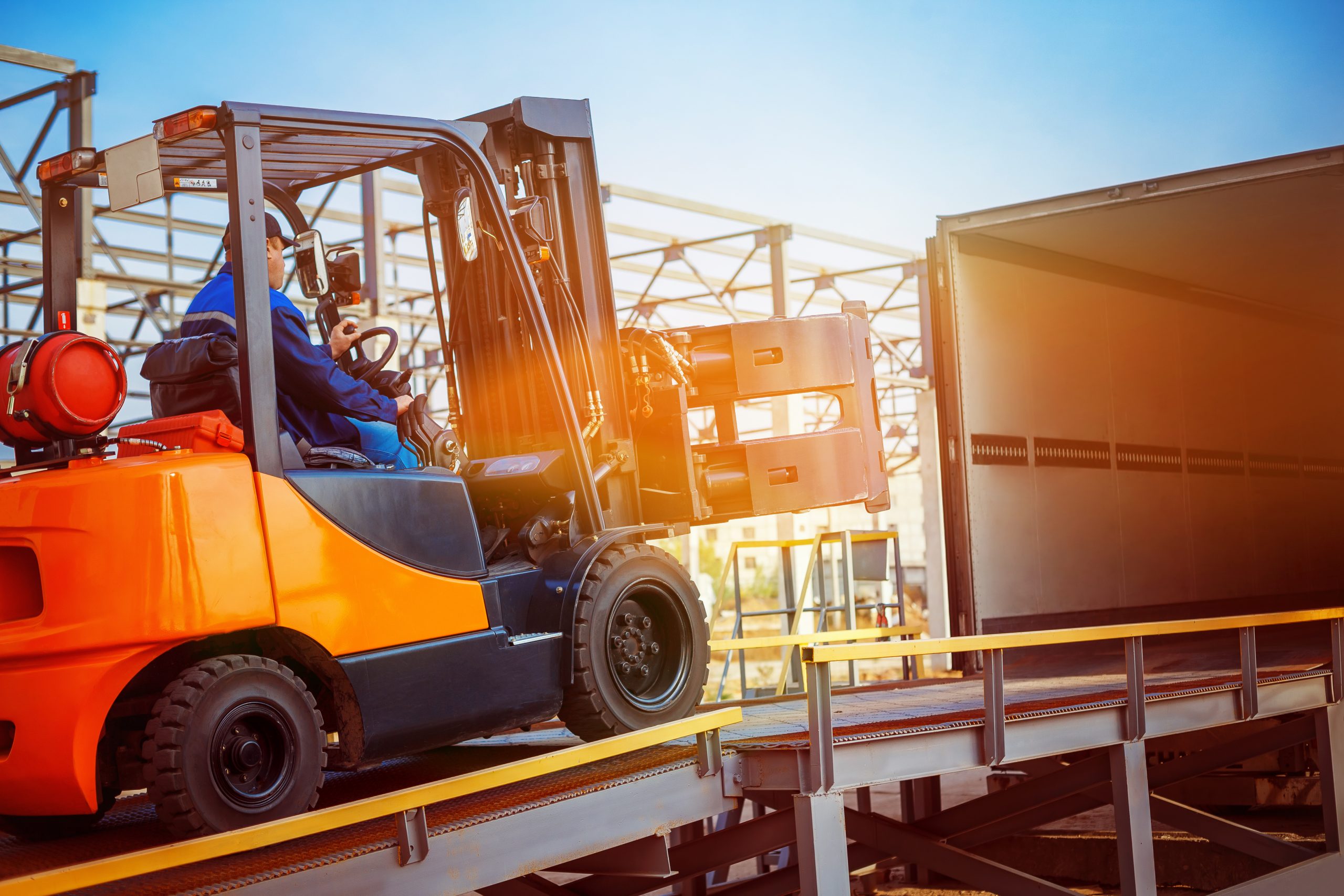 Forklift is putting cargo from warehouse to truck outdoors